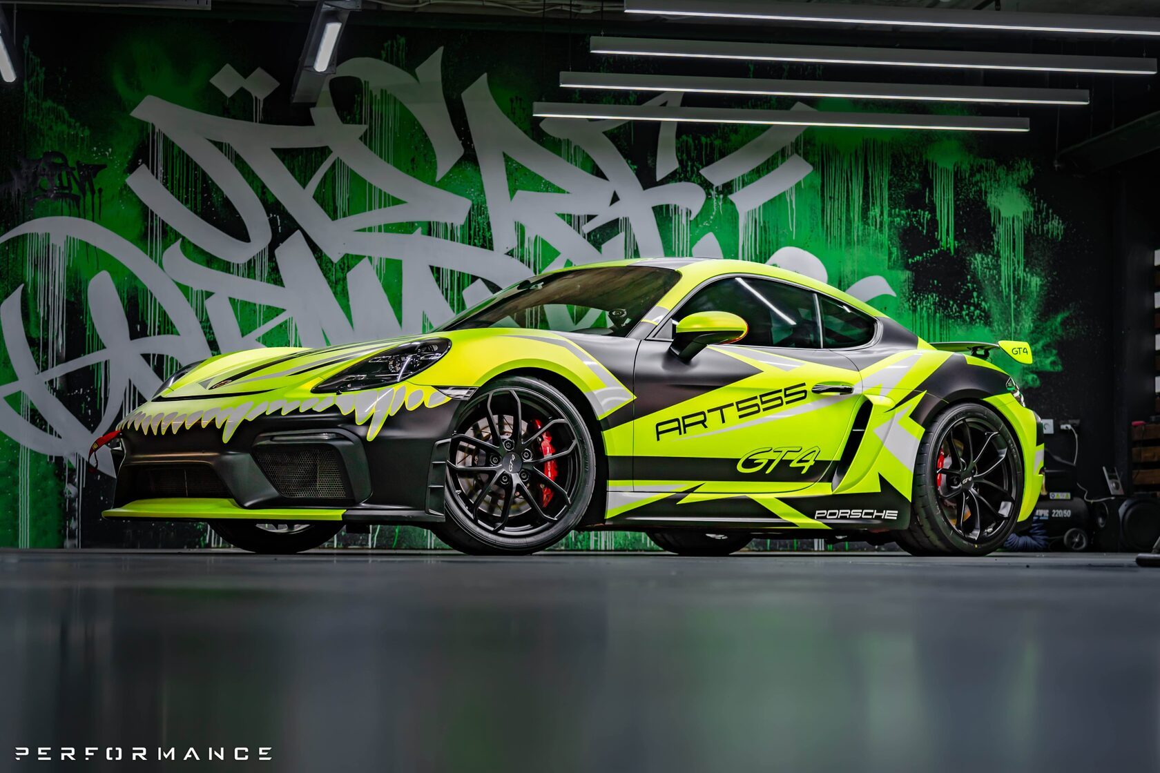 Porsche в салатовой плёнке на фоне расписанной стены бокса